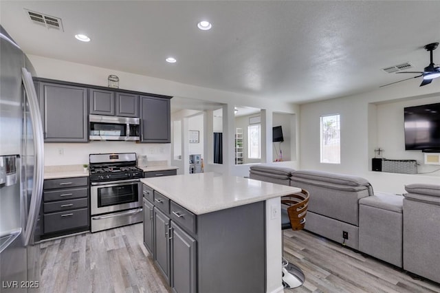 kitchen featuring visible vents, open floor plan, light wood-type flooring, appliances with stainless steel finishes, and gray cabinetry