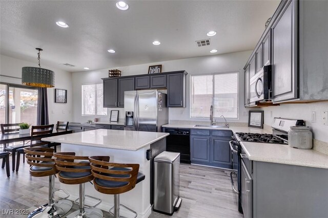 2929 Salado Creek Ave, North Las Vegas, NV 89081 - kitchen featuring stainless steel appliances, a sink, a kitchen island, light wood-style flooring, and light countertops
