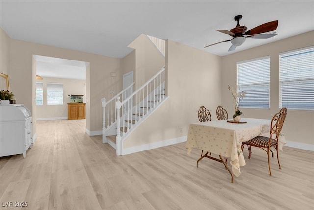 dining space with light wood finished floors, stairway, baseboards, and a ceiling fan