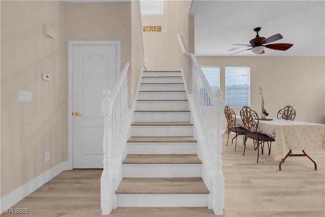staircase featuring wood finished floors, baseboards, and ceiling fan