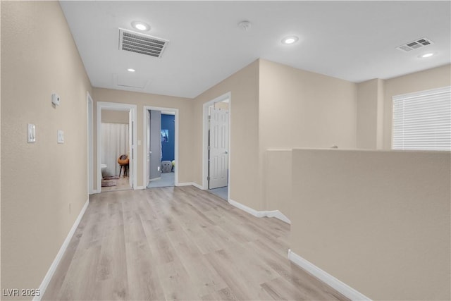 corridor featuring light wood-style floors, visible vents, and baseboards