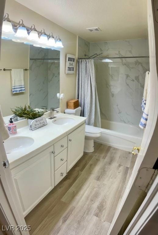 full bath with a sink, shower / bath combo, visible vents, and wood finished floors