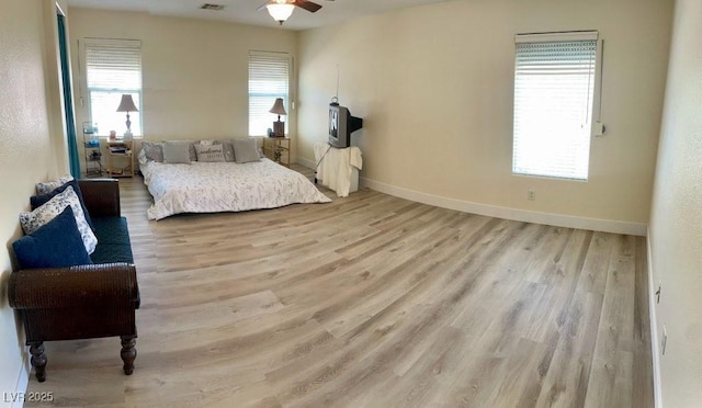 bedroom with multiple windows, light wood-style flooring, and baseboards