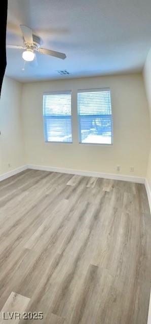 empty room with baseboards, visible vents, a ceiling fan, and wood finished floors