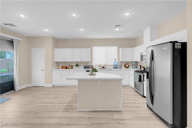 kitchen featuring a sink, stainless steel appliances, visible vents, white cabinetry, and light countertops