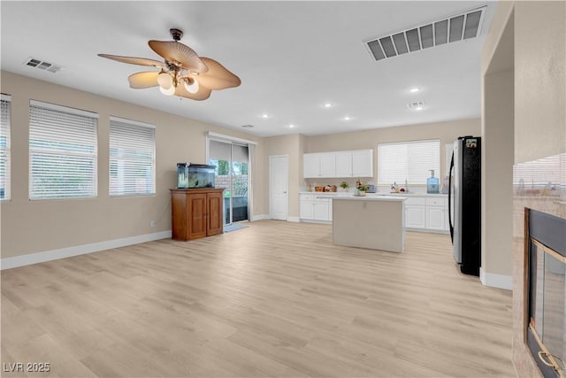 kitchen with freestanding refrigerator, light countertops, visible vents, and a kitchen island