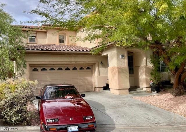 mediterranean / spanish-style home with concrete driveway, stucco siding, a tiled roof, and an attached garage