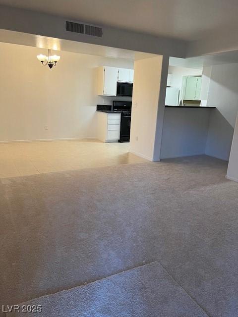 unfurnished living room with visible vents, carpet flooring, baseboards, and a chandelier