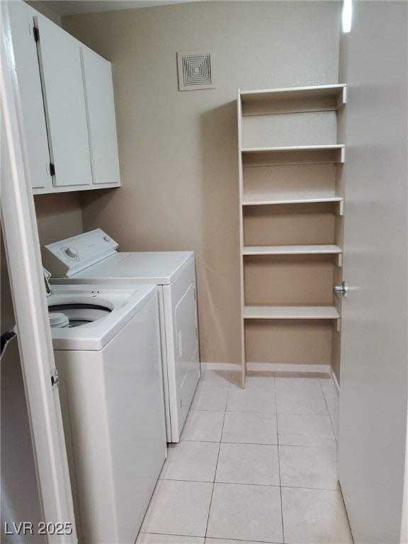 laundry area with visible vents, washing machine and clothes dryer, cabinet space, light tile patterned floors, and baseboards