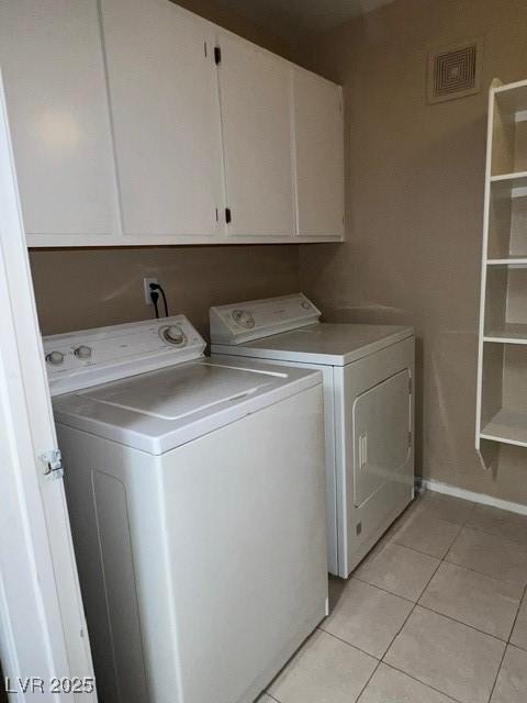 clothes washing area featuring visible vents, cabinet space, light tile patterned floors, baseboards, and washer and dryer