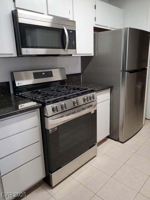 kitchen featuring light tile patterned floors, appliances with stainless steel finishes, and white cabinets