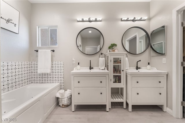 full bathroom featuring two vanities, a sink, and wood finished floors