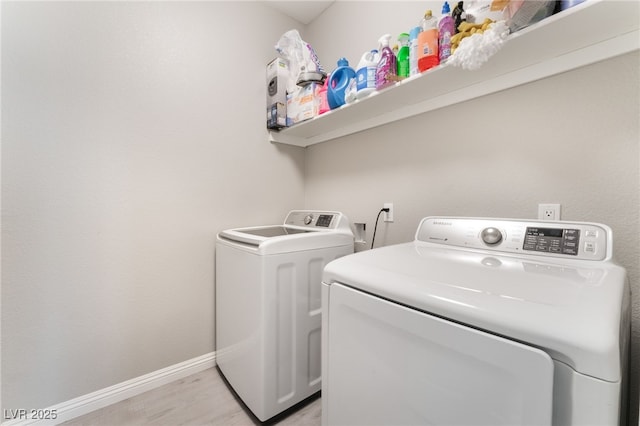 washroom featuring baseboards, laundry area, light wood finished floors, and washing machine and clothes dryer