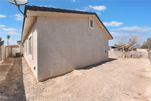 view of property exterior with central AC unit, stucco siding, and a fenced backyard