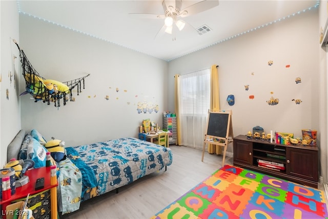 bedroom with a ceiling fan, visible vents, and wood finished floors