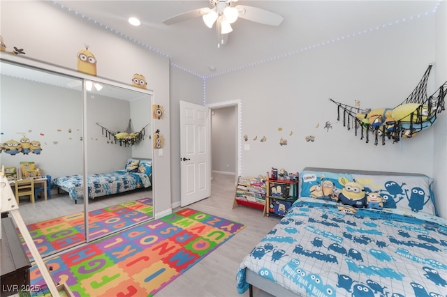 bedroom featuring baseboards, ceiling fan, wood finished floors, and a closet