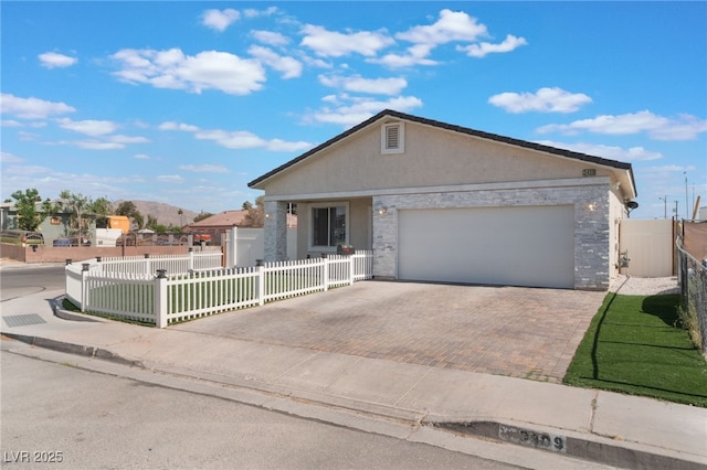 single story home featuring a garage, decorative driveway, a fenced front yard, and stucco siding