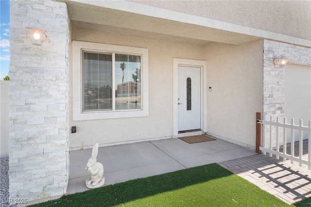 view of exterior entry with a garage and stucco siding