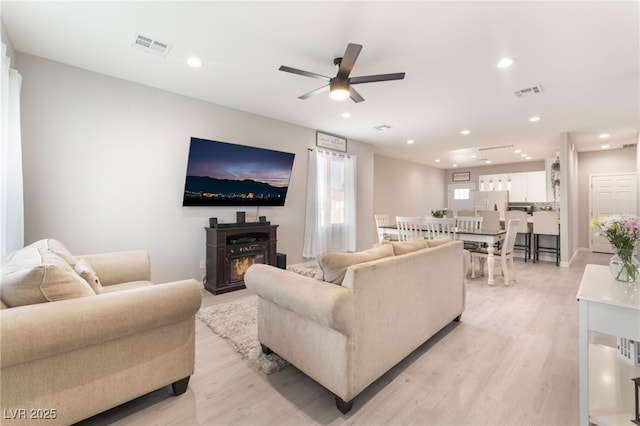 living room featuring recessed lighting, ceiling fan, light wood-type flooring, and visible vents