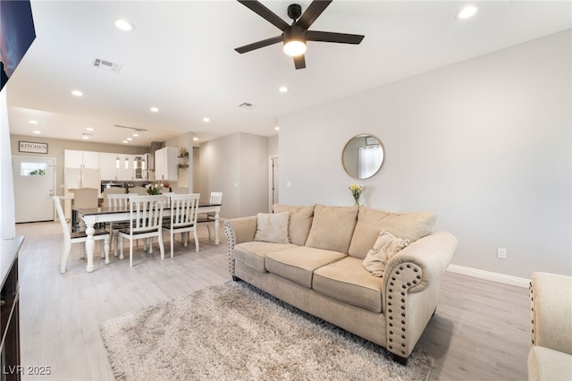 living room with light wood-type flooring, a ceiling fan, visible vents, and recessed lighting