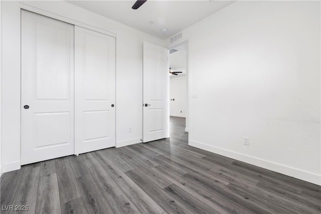 unfurnished bedroom featuring ceiling fan, baseboards, wood finished floors, visible vents, and a closet