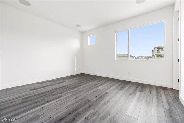 spare room with baseboards and wood finished floors