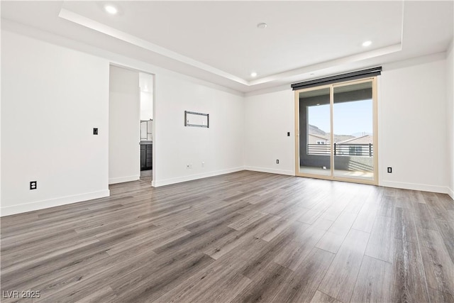 unfurnished room featuring baseboards, recessed lighting, a tray ceiling, and wood finished floors
