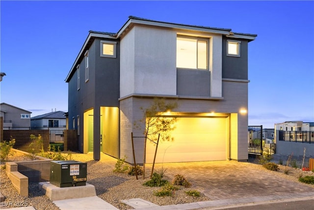 contemporary home featuring fence, a residential view, decorative driveway, and a garage