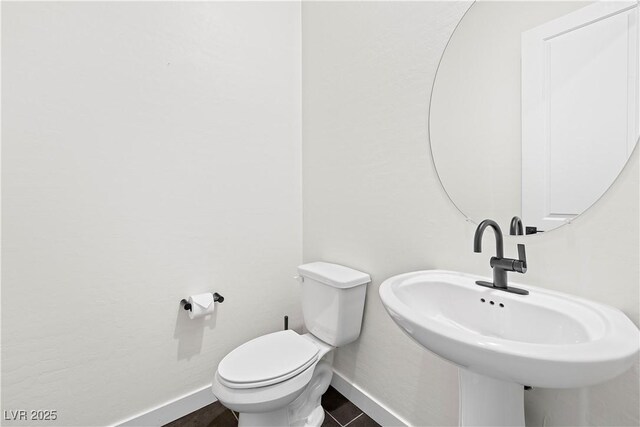 half bathroom featuring a sink, baseboards, and toilet