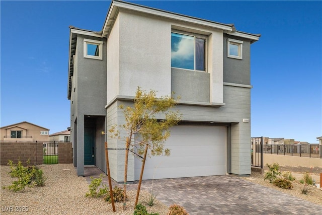 view of front of home with stucco siding, fence, driveway, and a garage