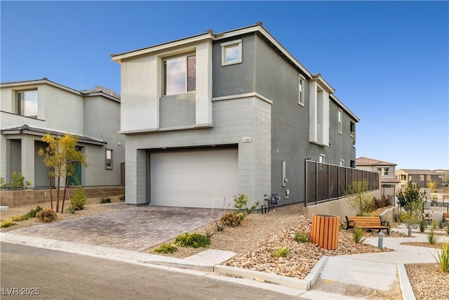 view of front of property featuring decorative driveway, a garage, and stucco siding