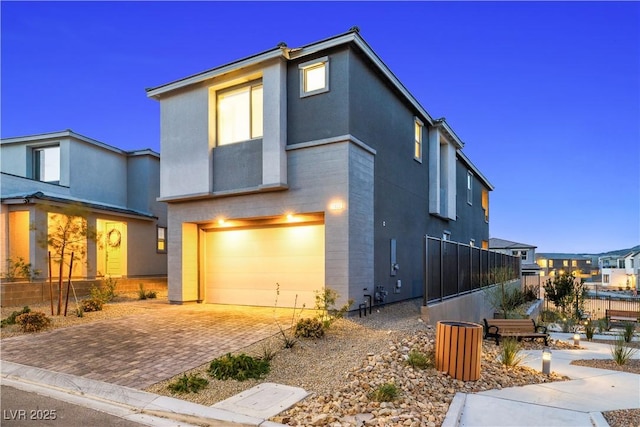 modern home with an attached garage, stucco siding, and decorative driveway