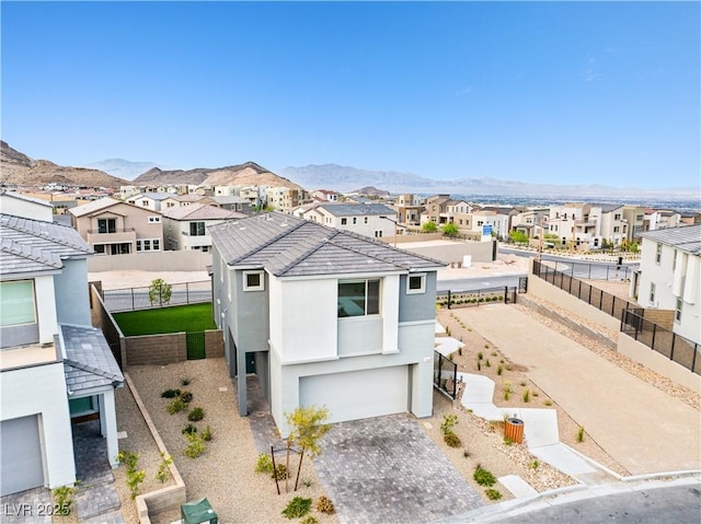 view of front facade featuring a garage, decorative driveway, stucco siding, a mountain view, and a residential view