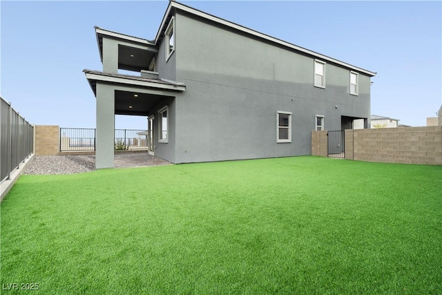 rear view of property featuring a fenced backyard, stucco siding, and a lawn