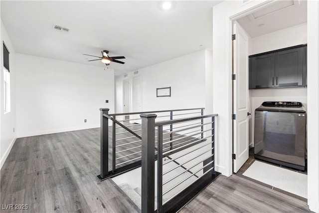 interior space featuring washer / clothes dryer, baseboards, an upstairs landing, wood finished floors, and visible vents