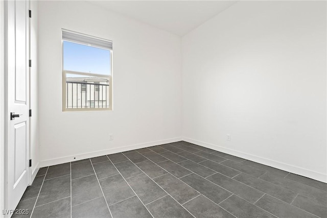 unfurnished room with baseboards and dark tile patterned floors