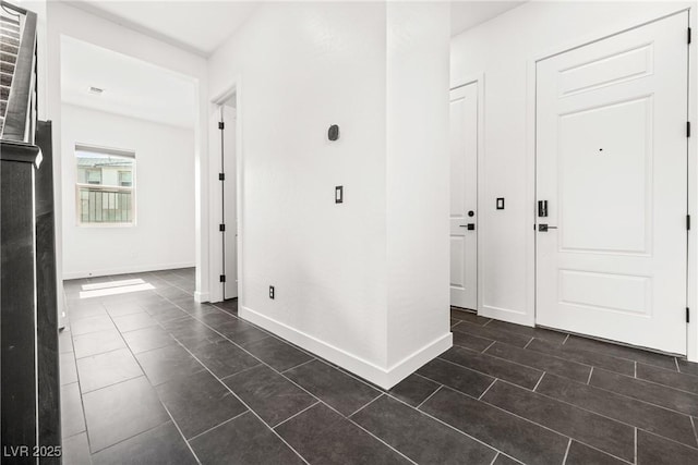 foyer entrance featuring baseboards and dark tile patterned flooring
