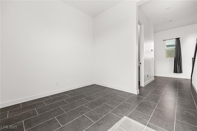 spare room with dark tile patterned flooring and baseboards