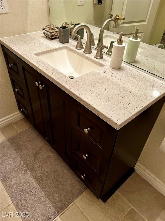 bathroom featuring baseboards, a textured wall, and vanity