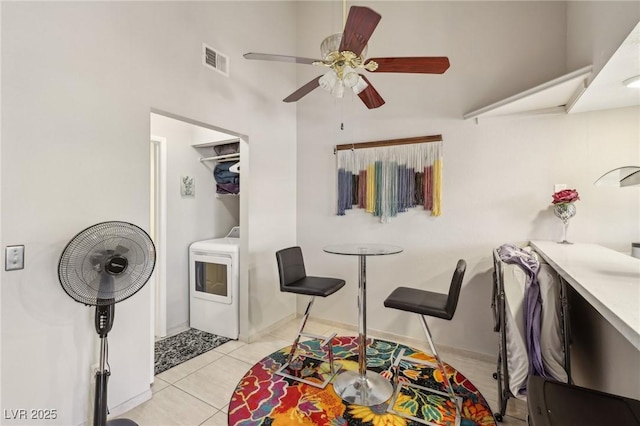 interior space featuring ceiling fan, visible vents, light tile patterned floors, baseboards, and washer / dryer