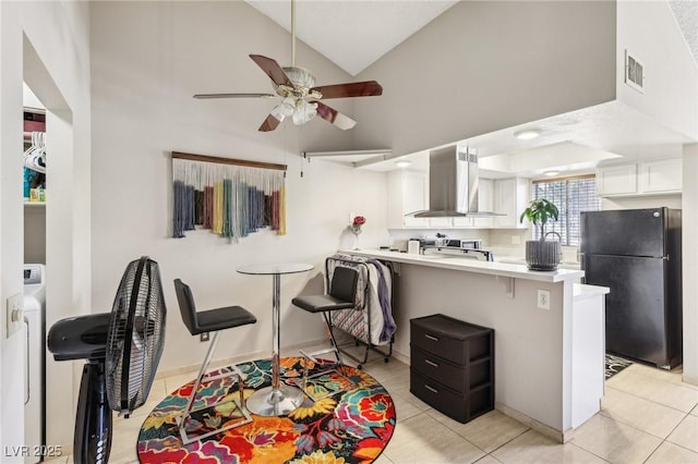 kitchen with visible vents, freestanding refrigerator, a peninsula, white cabinetry, and exhaust hood