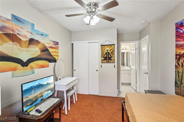 bedroom featuring a ceiling fan, a textured ceiling, light colored carpet, a closet, and ensuite bathroom