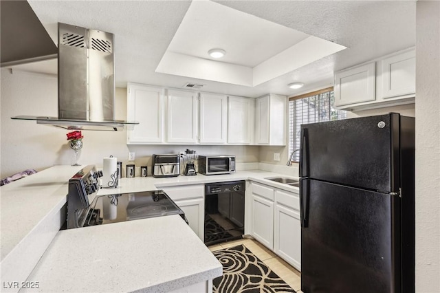 kitchen with a raised ceiling, white cabinets, island exhaust hood, a sink, and black appliances