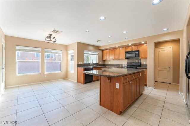 7098 Seabirds Pl, North Las Vegas, NV 89084 - kitchen with black appliances, a center island, light tile patterned flooring, recessed lighting, and a kitchen bar