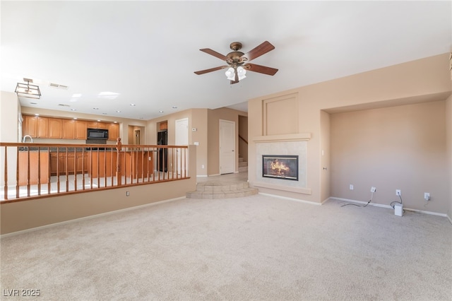 unfurnished living room featuring baseboards, a ceiling fan, light carpet, and a tile fireplace