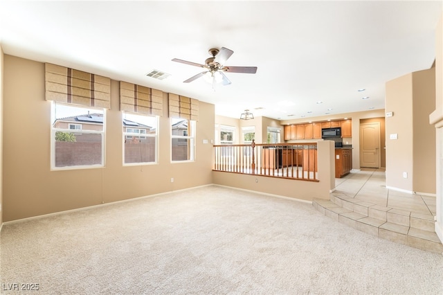 unfurnished living room featuring a ceiling fan, baseboards, visible vents, and light carpet
