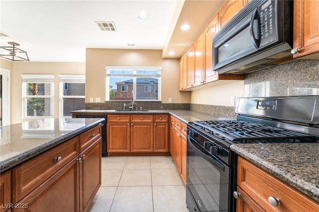 kitchen with visible vents, a sink, black appliances, dark stone countertops, and light tile patterned flooring