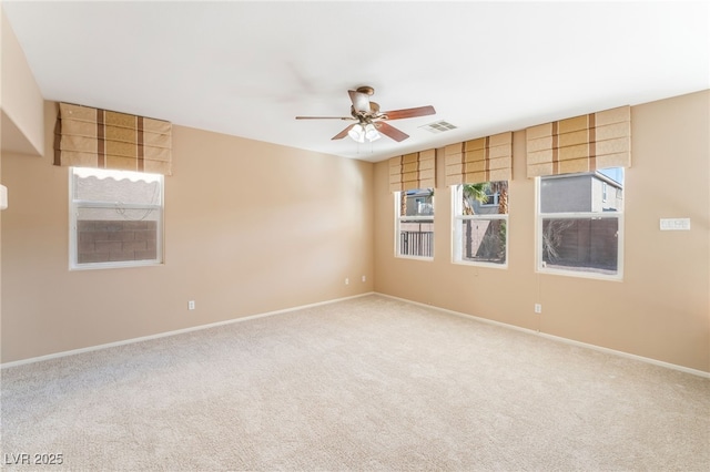 carpeted empty room with visible vents, baseboards, ceiling fan, and a healthy amount of sunlight