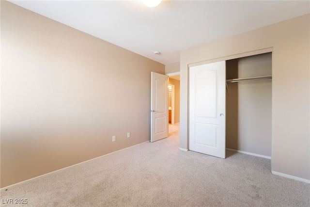 unfurnished bedroom featuring baseboards, light carpet, and a closet