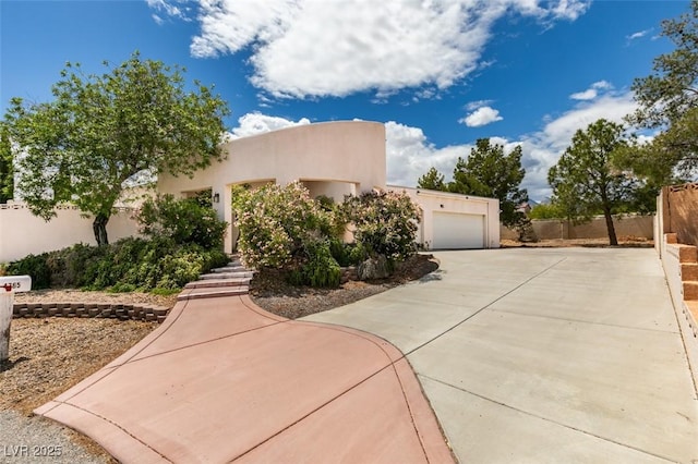 view of front facade featuring fence, stucco siding, concrete driveway, and a garage